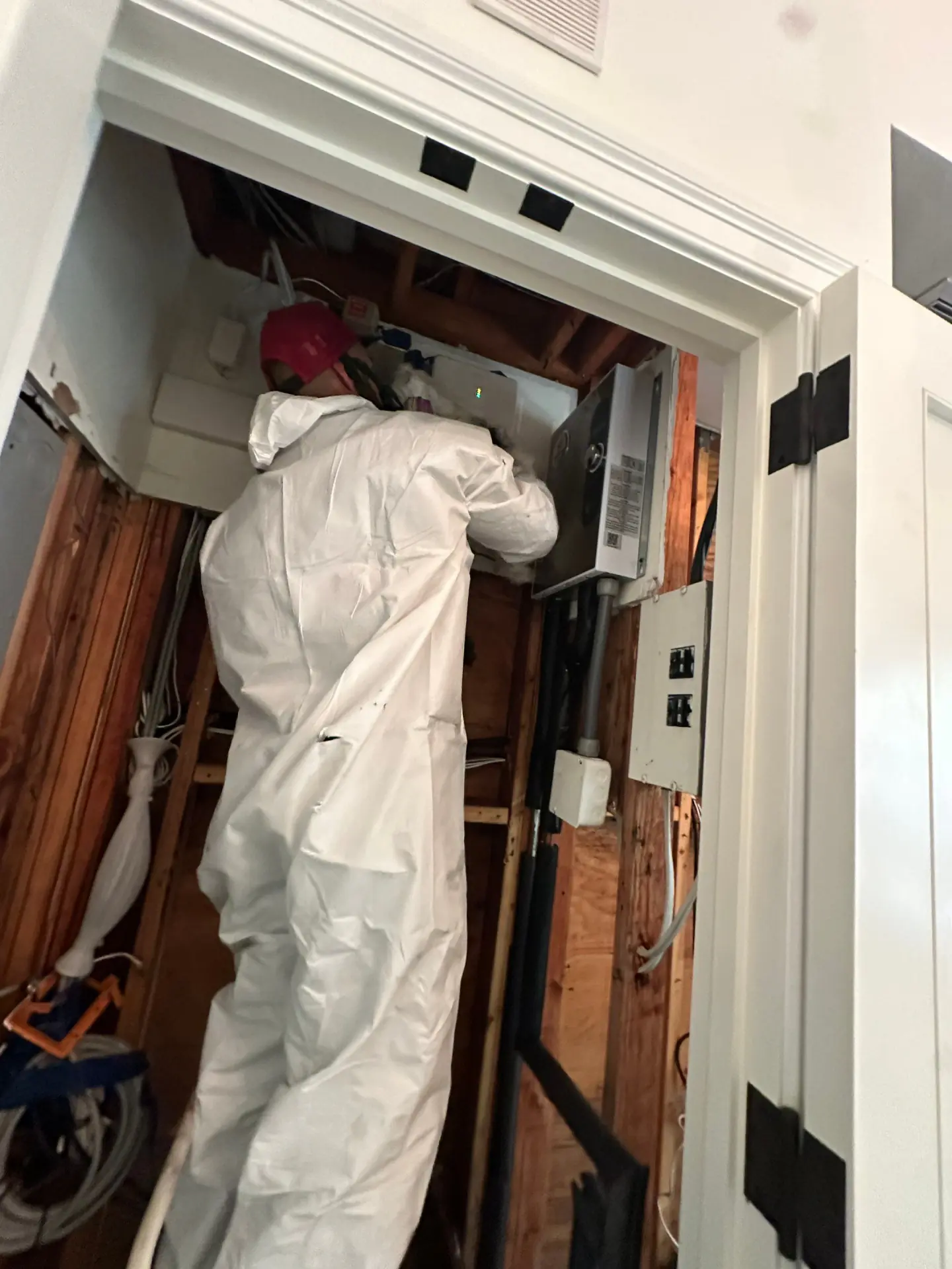 K.O.S. technician in a suit working inside a stripped utility closet after a water loss